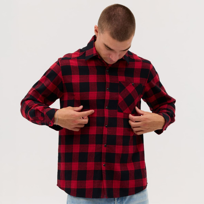 A flannel long sleeve shirt in red and black check pattern, featuring a front pocket and button closures.