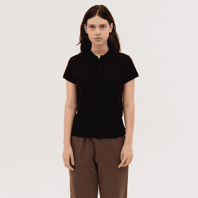 A black women's polo shirt featuring a collar and short sleeves, paired with brown trousers. It has a logo on the garment.
