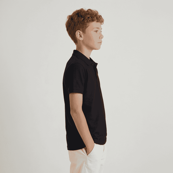 A black polo shirt for youth displayed on a model, featuring a classic design and a logo on the chest.