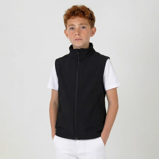 A black softshell vest featuring a high collar and zip closure, modelled by a child against a plain backdrop.