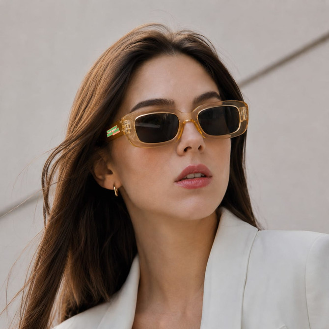 Vintage rectangle sunglasses in a light brown hue, featured on a model with long hair, set against a neutral background.