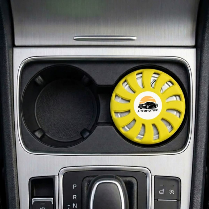 A round, yellow air freshener is placed in a car cup holder, featuring a logo and a vented design.