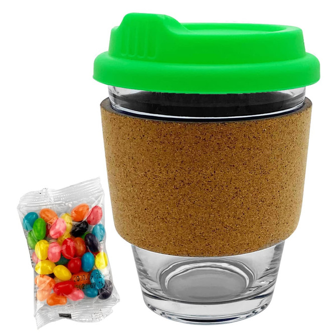 A glass coffee cup with a cork band and a bright green lid, accompanied by a pack of colourful jelly beans.