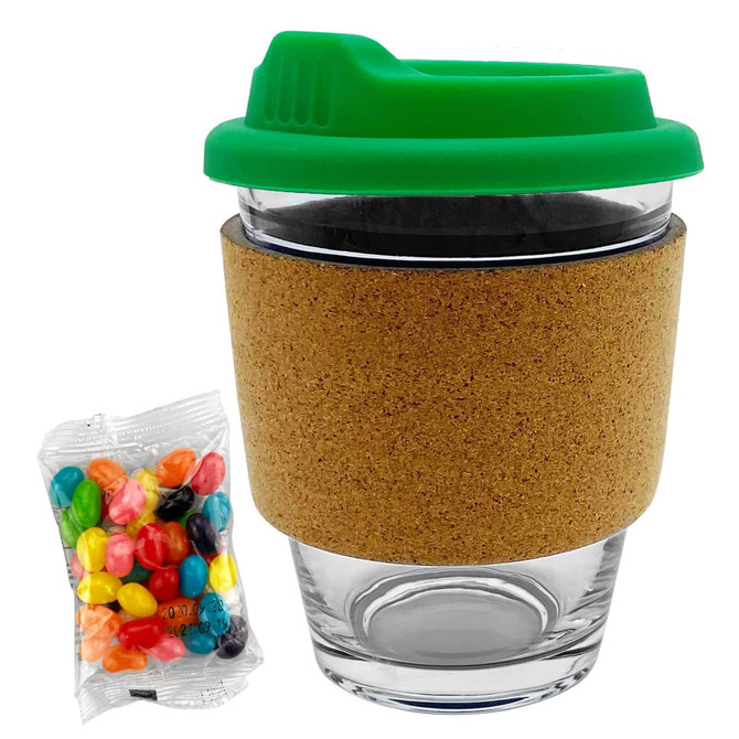 A glass coffee cup with a green lid and cork band, accompanied by a pack of colourful jelly beans.