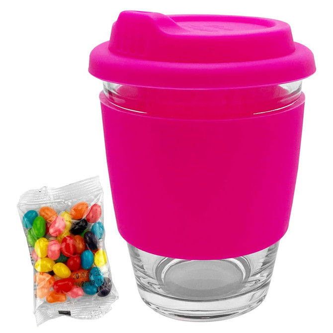 A pink silicone-covered glass coffee cup with a lid, accompanied by a bag of colourful jelly beans.