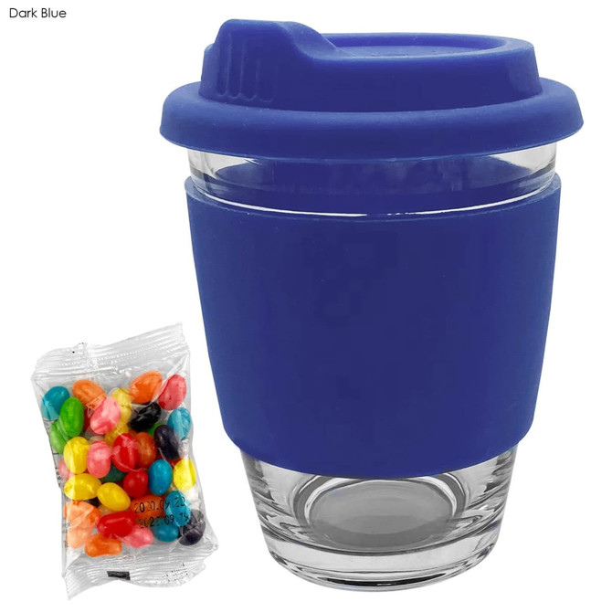A dark blue coffee cup with a silicone lid and a clear glass body, accompanied by a bag of colourful jelly beans.