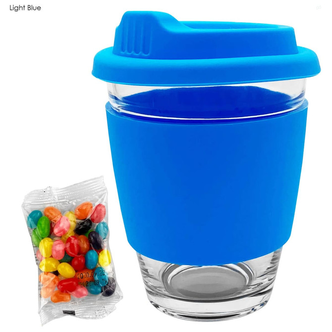 A glass coffee cup with a light blue silicone lid and sleeve, accompanied by a pack of colourful jelly beans.
