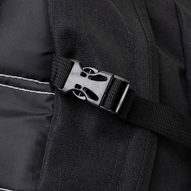 A close-up of a black backpack strap featuring a plastic buckle and stitched detailing.