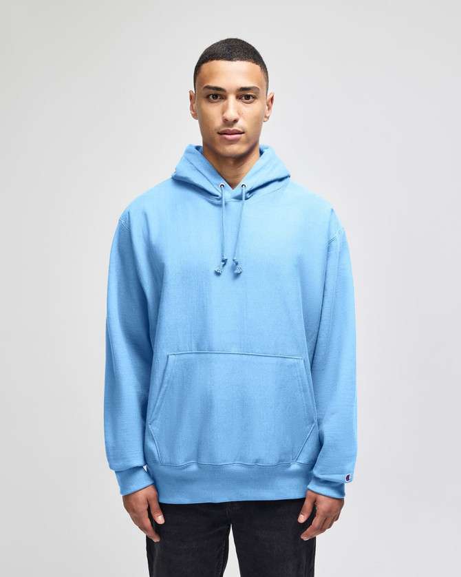 A blue Champion Reverse Weave® adult pullover hooded sweatshirt on a model, featuring a front pocket and a hood.