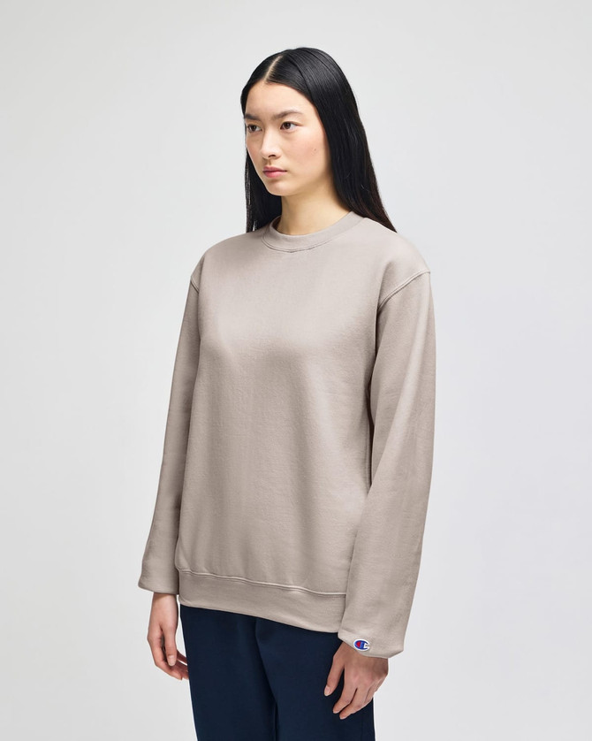 A beige crewneck sweatshirt with long sleeves, featuring a small logo on the sleeve.