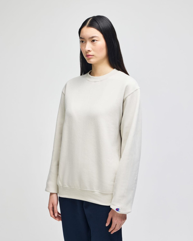 A light beige adult crewneck sweatshirt with a relaxed fit and a small logo.