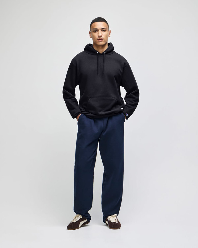 A black hooded sweatshirt paired with navy pants, featuring a logo on the sweatshirt.