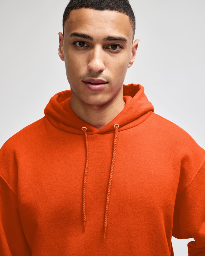 An orange pullover hooded sweatshirt is worn by a model, featuring a drawstring hood.