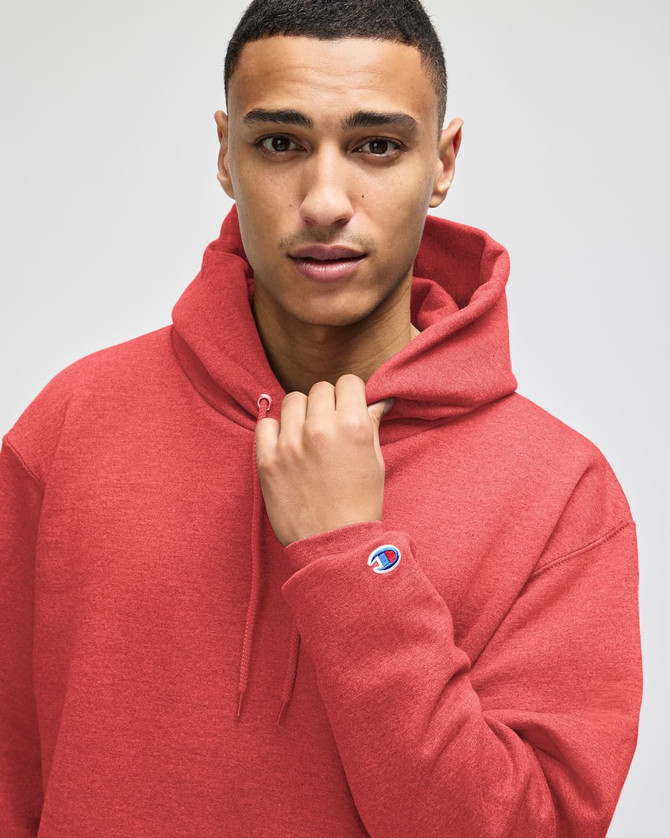 A red pullover hooded sweatshirt with a logo on the sleeve, worn by a model with a neutral expression.