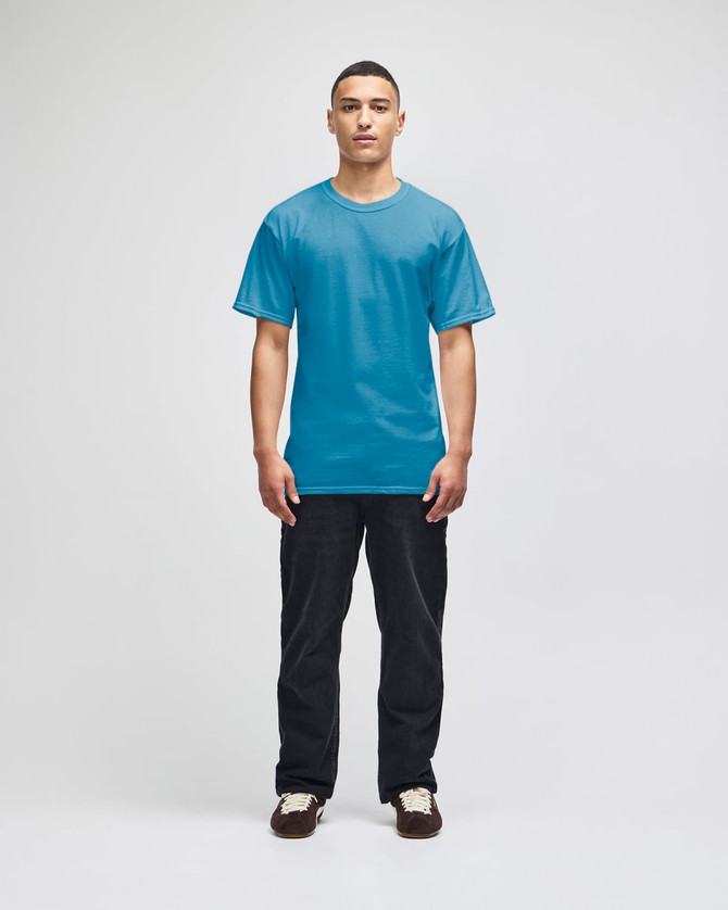 A man wearing a bright blue short-sleeve t-shirt and black pants, standing against a plain background.