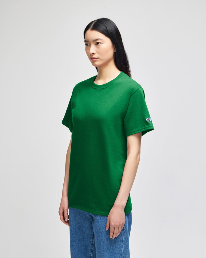 A green Champion adult short-sleeve t-shirt displayed on a model, featuring a logo on the sleeve.
