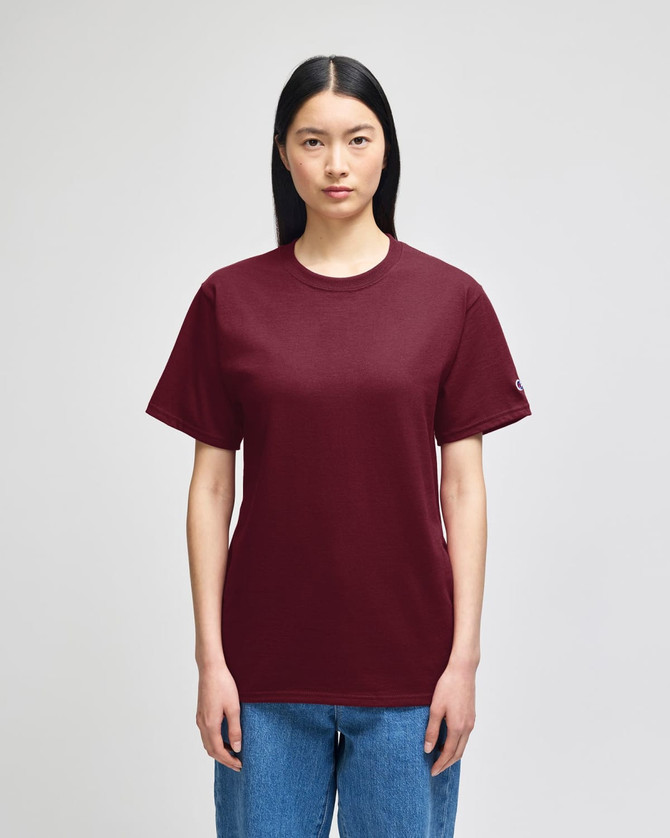 A maroon short-sleeve T-shirt displayed on a model, featuring a small logo on one sleeve.