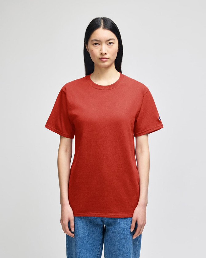 A red short-sleeve t-shirt with a logo, displayed on a model in casual denim jeans.