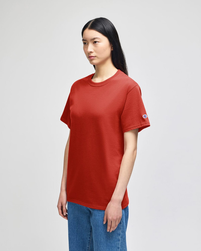 A red Champion adult short-sleeve t-shirt displayed on a model, featuring a logo on the sleeve.