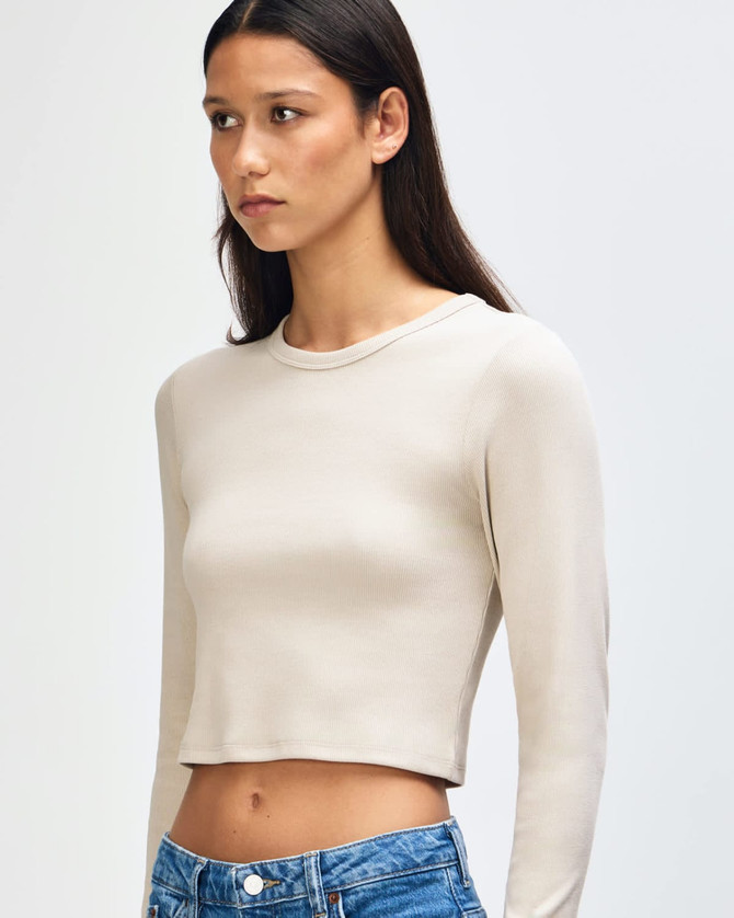 A fitted long-sleeve crop top in beige, featuring a round neckline and a slim silhouette. It has a logo.