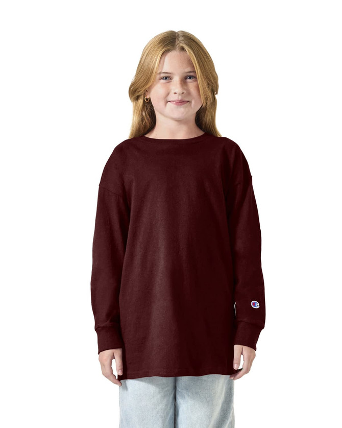 A youth long sleeve t-shirt in burgundy, featuring a loose fit and a logo on the sleeve.