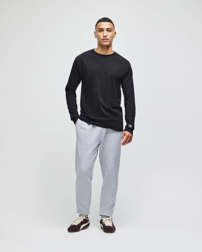 A model wearing a black long-sleeve top and light grey fleece jogger pants, featuring a logo on the joggers.