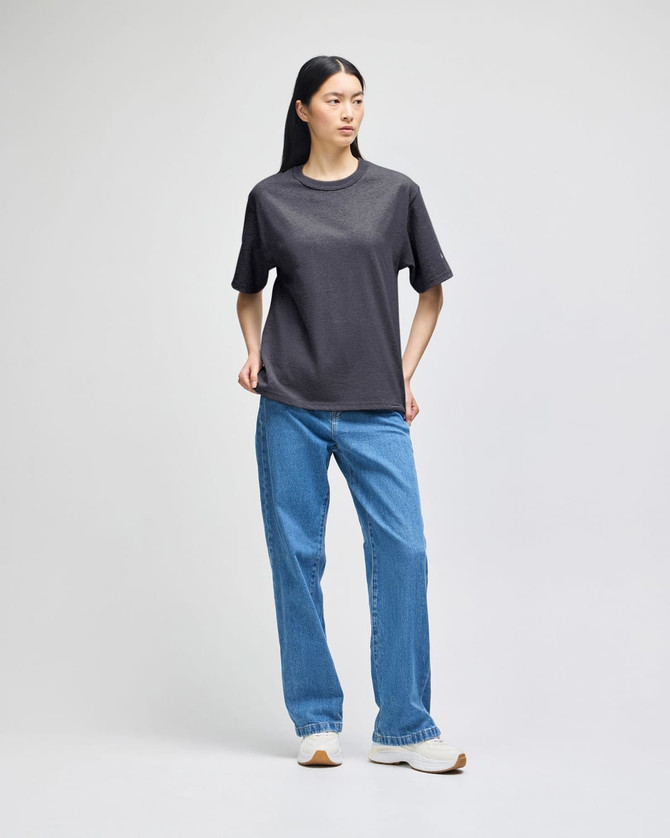 A grey T-shirt displayed on a model, paired with blue jeans. The shirt features a logo.