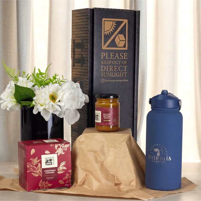 A blue drink bottle, a jar, a box, and a vase with flowers arranged on brown packaging.