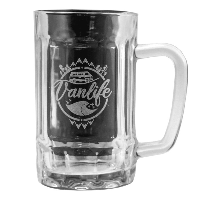 A clear beer glass with a handle features an etched design including a van, mountains, and waves.