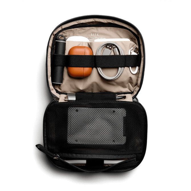 A black tech kit opened to reveal a drink bottle, orange case, cords, and a mesh pocket.
