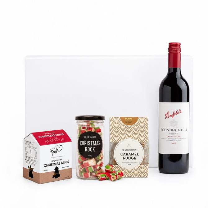 A drink bottle of red wine alongside Christmas-themed sweets: fudge, rock candy, and chocolate minis.