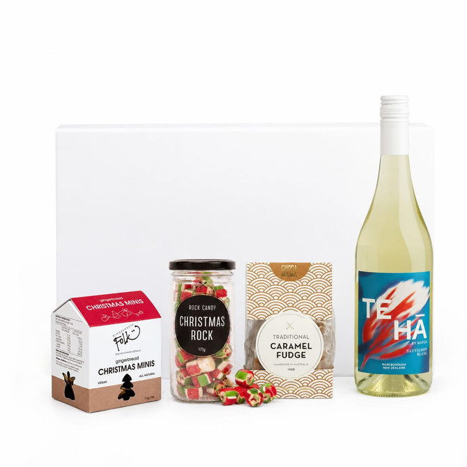 A drink bottle of white wine, alongside Christmas-themed sweets and fudge in decorative packaging.