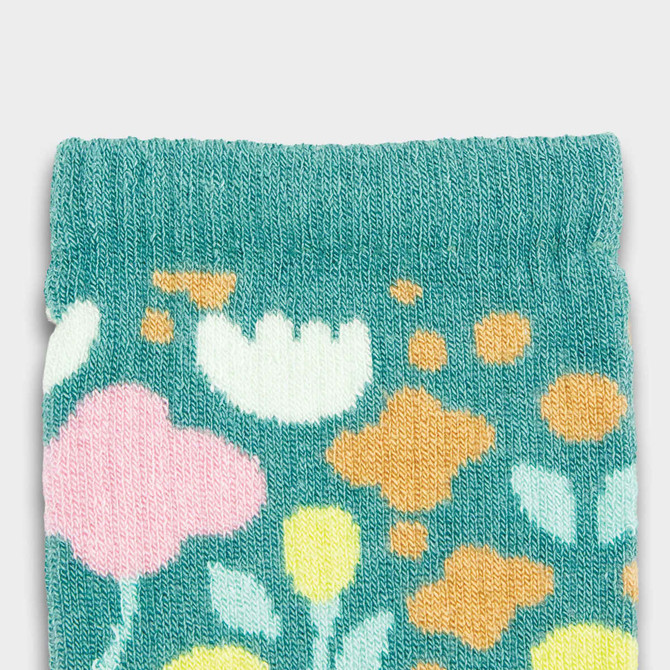 A close-up of light teal kids' socks featuring a colourful floral pattern in pink, yellow, and white.