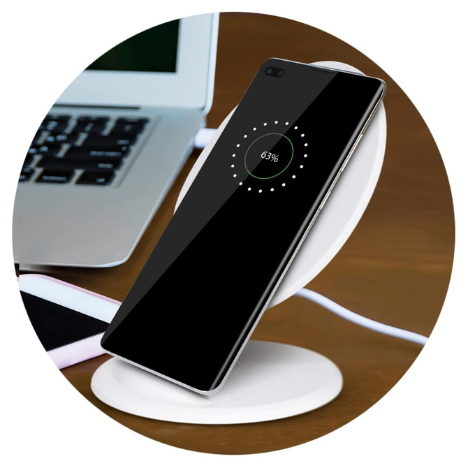 A wireless charging stand in white with a smartphone displaying charging progress, placed on a wooden surface.