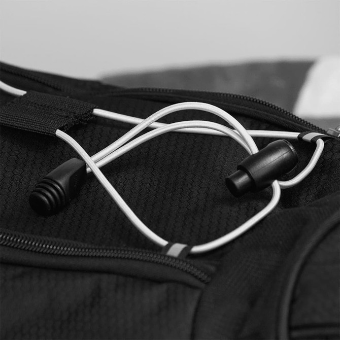 A close-up of black fabric with white cords and a connector, featuring a logo on the duffel bag.