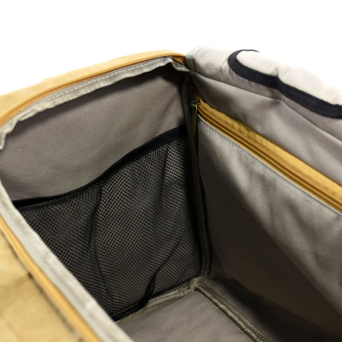 An interior view of a tan kraft paper duffle bag featuring a zippered pocket and a mesh compartment.