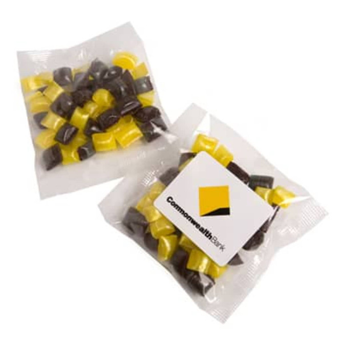 A clear bag containing a mix of black and yellow humbug sweets, featuring a logo on the packaging.