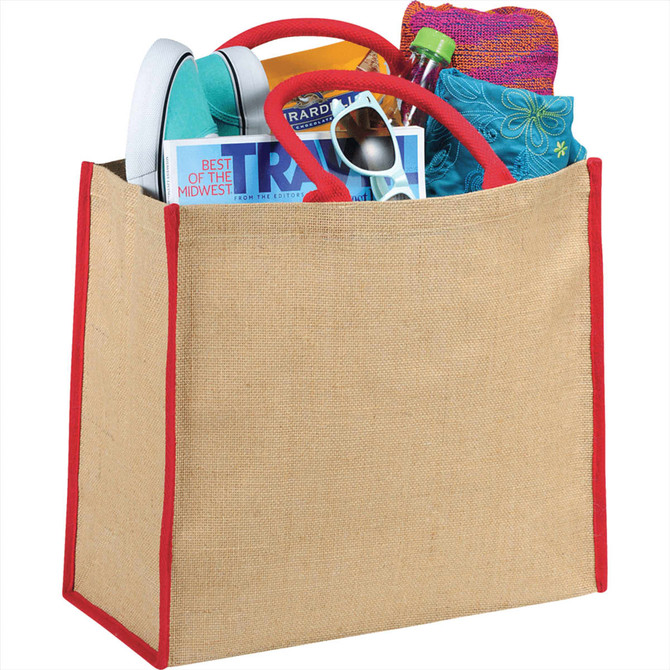 A large jute tote in natural colour with red trim, filled with a drink bottle, magazines, sunglasses, and a towel.