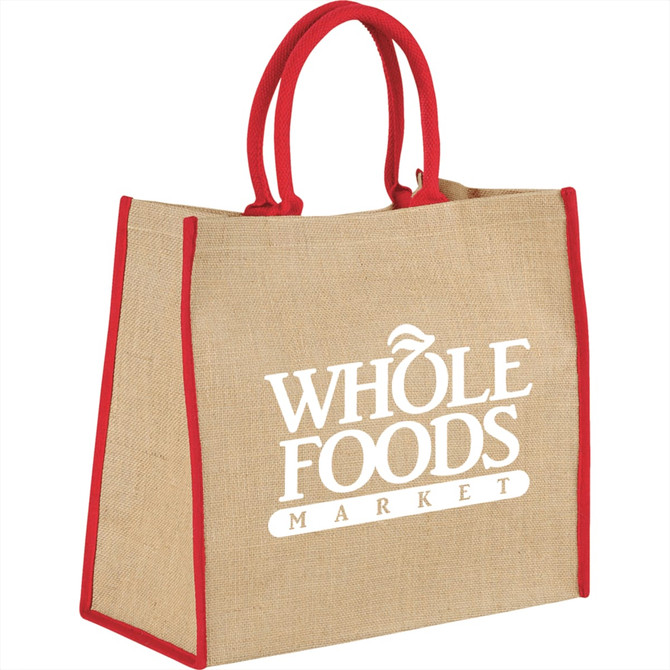 A large jute tote bag in beige with red handles and trim, featuring a logo on the front.