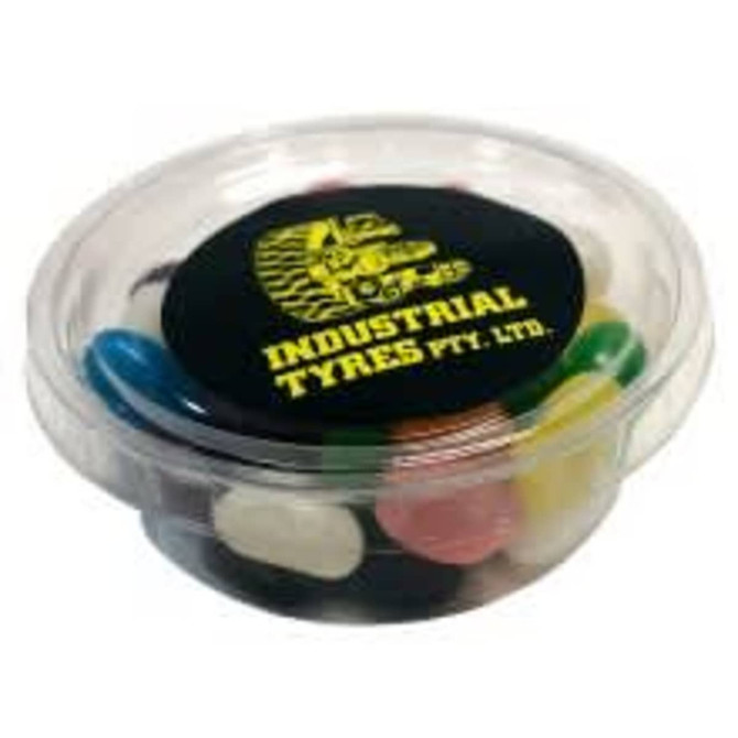 A clear tub filled with colourful jelly beans, including blue, pink, green, and white, featuring a branded lid.