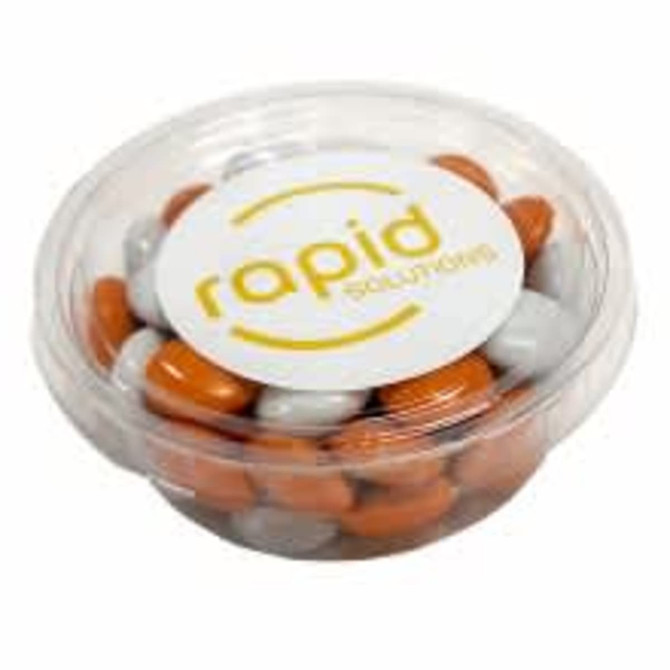 A clear tub filled with orange and grey choc beans, featuring a logo on the lid.