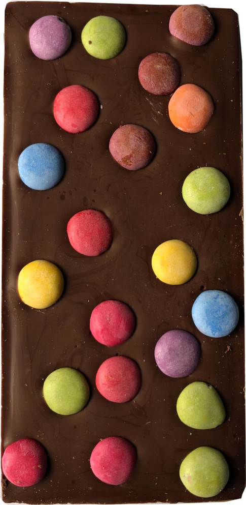 A milk chocolate bar with colourful round candy spots in pink, blue, yellow, and green on top.