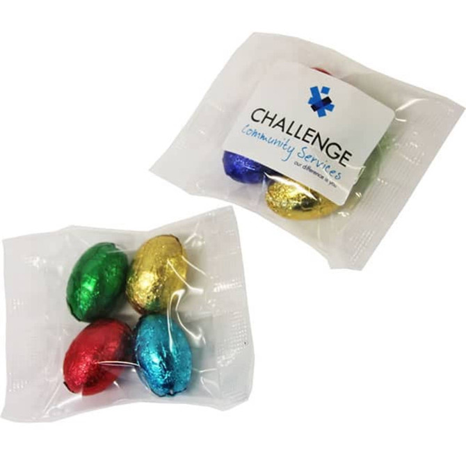 Mini solid Easter eggs wrapped in shiny foil, featuring red, green, blue, and gold colours, in a clear plastic bag.