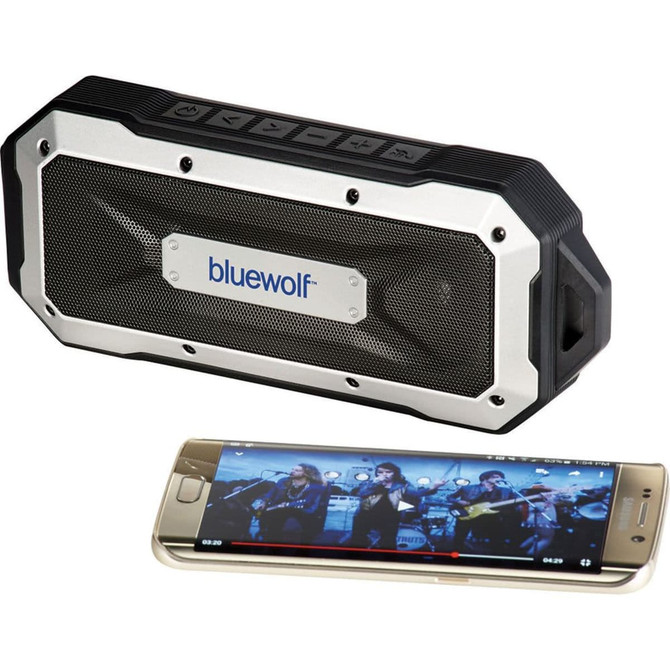 A black and silver waterproof Bluetooth speaker beside a smartphone displaying a music video. The speaker features a logo.