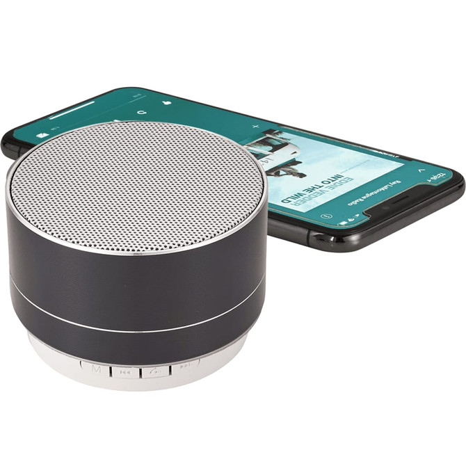 A black aluminium Bluetooth speaker next to a smartphone, showcasing its compact design and modern features.