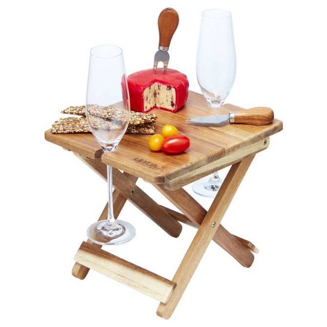A foldable wooden cheese and wine board with a cheese block, knife, crackers, and two glasses.