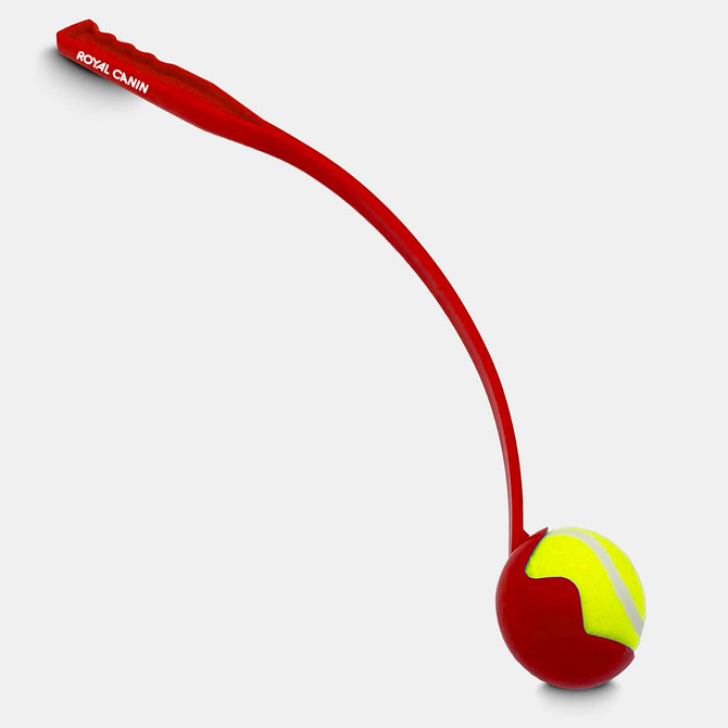 A red ball launcher with a yellow tennis ball, designed for pet play. It features a branding logo on the handle.