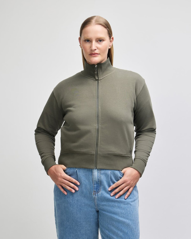 A women's full-zip jacket in olive green, featuring a high collar and ribbed cuffs, with a logo on the sleeve.