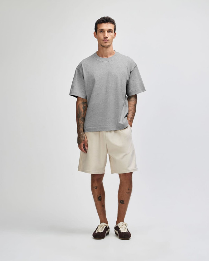 A model wearing a grey heavyweight cotton unisex boxy t-shirt paired with black wide-legged pants.