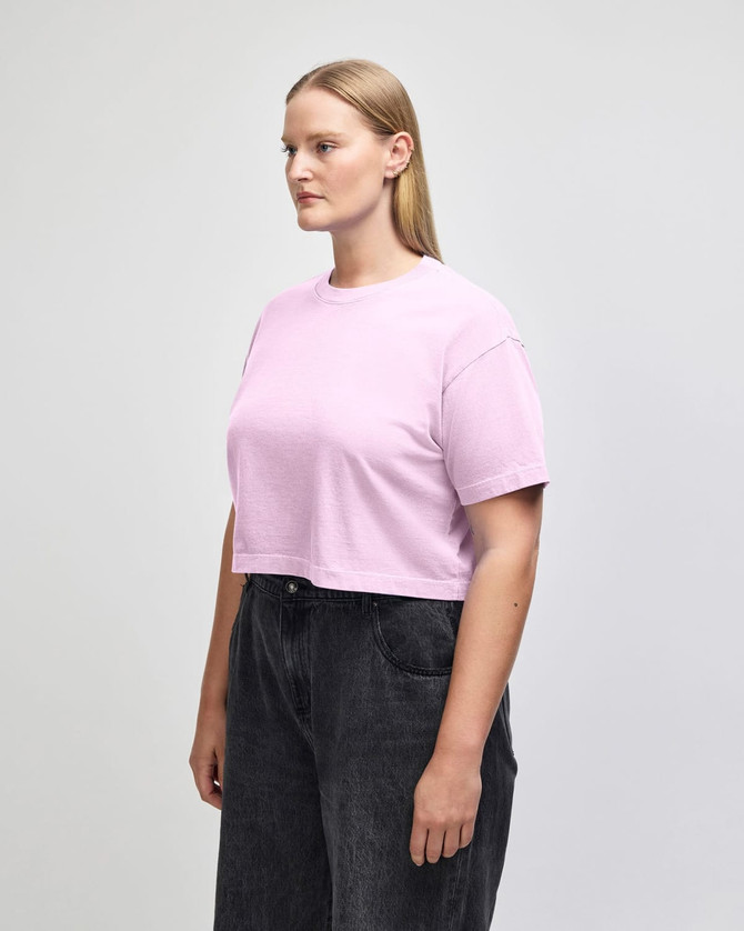 A pale pink women's crop boxy T-shirt, featuring a relaxed fit and short sleeves, worn with blue jeans.